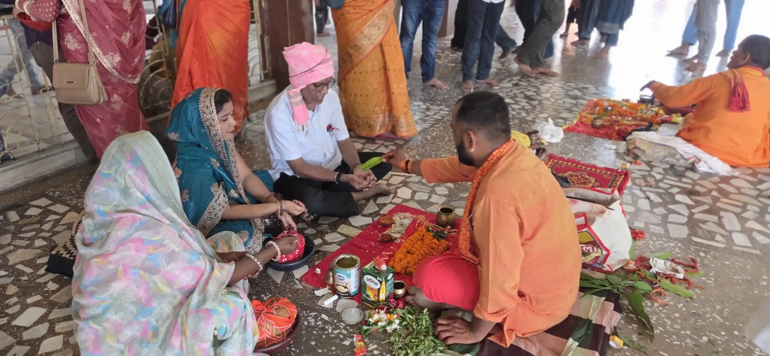माँ कामाख्या धाम गहमर में पंडित जी के साथ फर्श पर बैठकर विधि-विधान से पूजा करते श्रद्धालु परिवार।