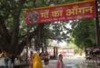 माँ कामाख्या धाम, गहमर, गाजीपुर के मंदिर परिसर में स्थित विशाल वटवृक्ष के नीचे नया बना छायेदार स्थान 'माँ का आँगन'। तस्वीर में लाल रंग का स्वागत बोर्ड, बरगद का पेड़ और श्रद्धालु दिखाई दे रहे हैं।"